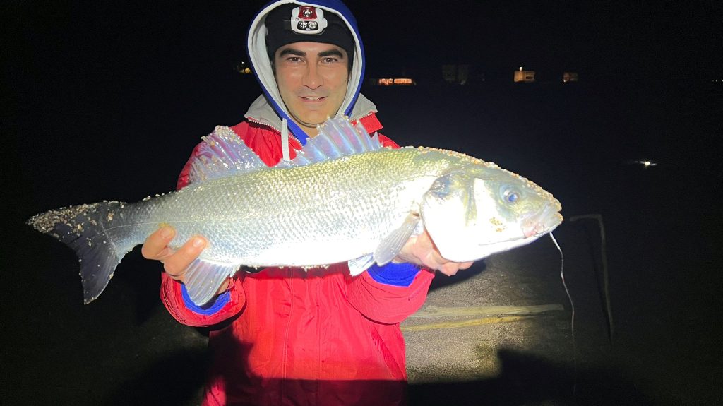 Hombre exhibiendo un gran pez, pesca nocturna