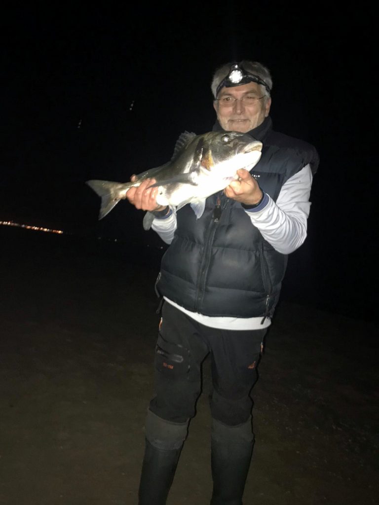 Hombre exhibiendo un gran pez, pesca nocturna